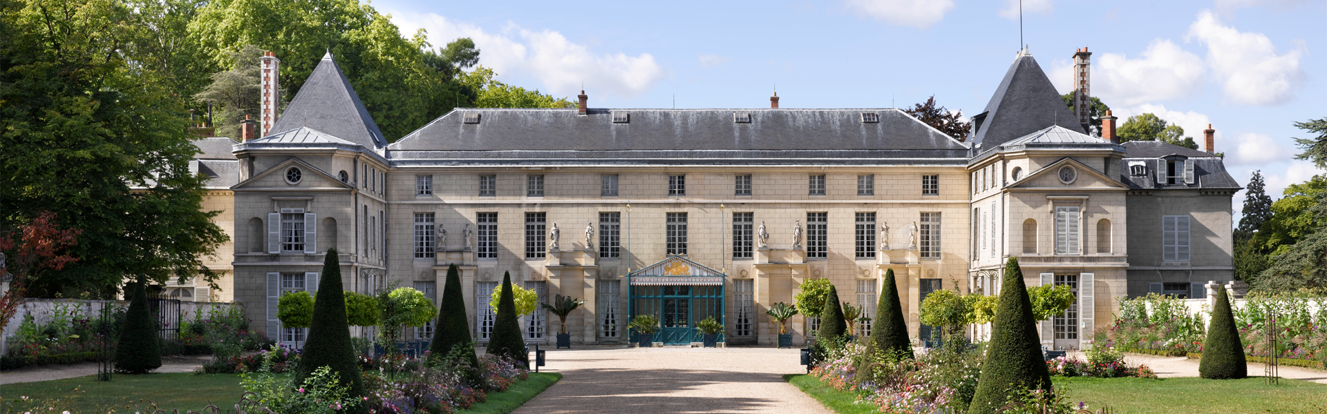 Vue extérieure du château de Malmaison depuis l'allée centrale, bordée de parterres de fleurs