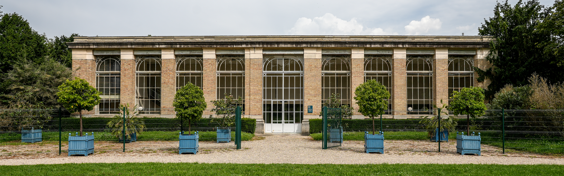 Orangerie du parc de Bois-Préau aux grandes fenêtres vitrées entourée de verdure