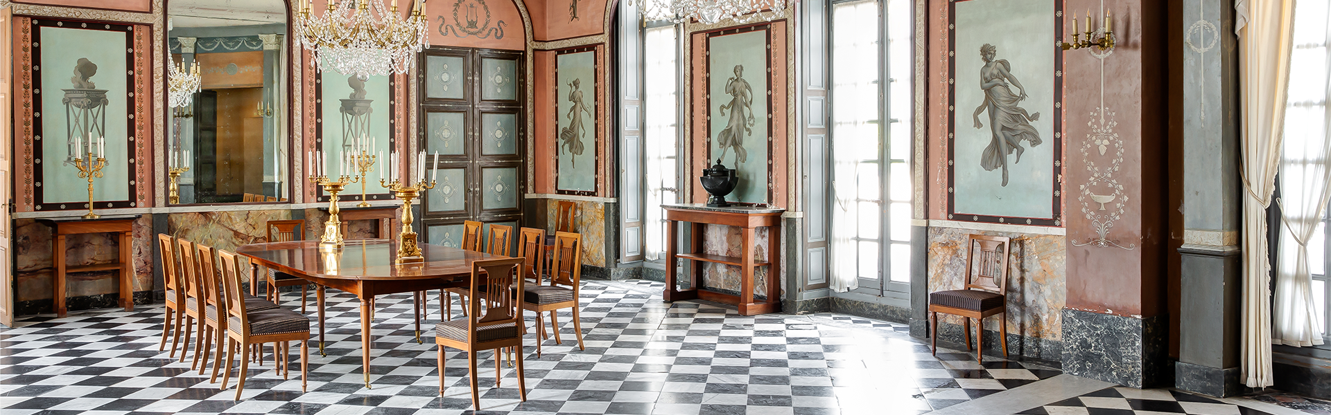 Pièce ornée de fresques pompéiennes, avec une longue table et un sol en damier noir et blanc