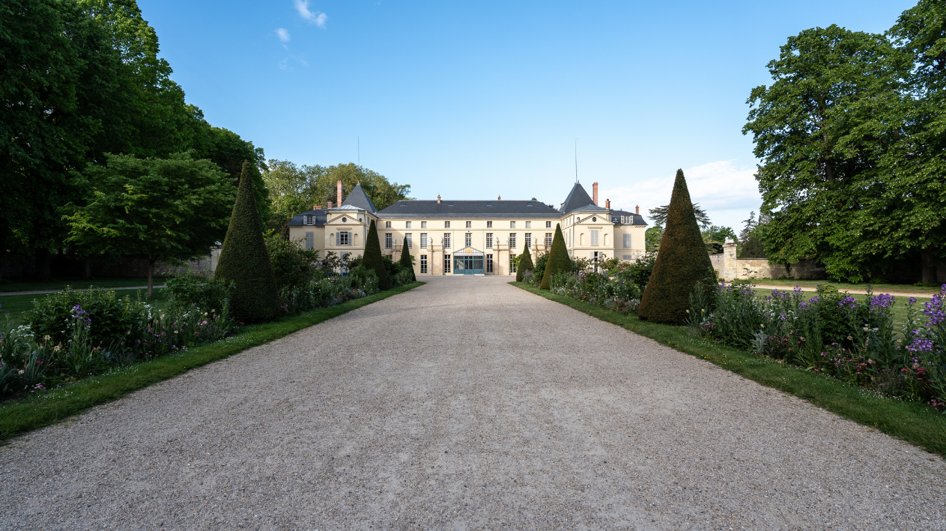 Vue au loin de la façade principale du château de Malmaison depuis l'entrée de la grille d'honneur
